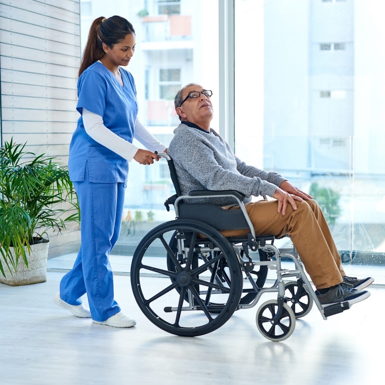 Shot of a young nurse pushing a senior man in a wheelchair