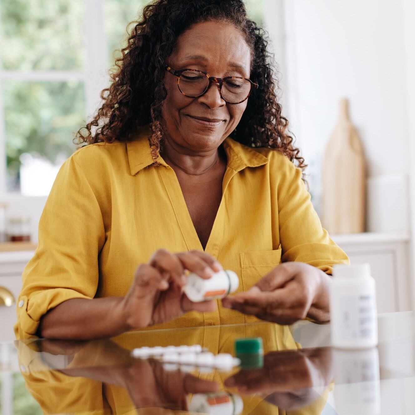 Senior woman carefully taking her prescription medication as part of her daily routine. Mature woman committing to her treatment plan as part of her chronic disease management at home.